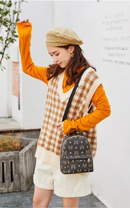 Détail du mini sac à dos marron foncé avec monogramme doré et bretelles en nylon