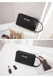 Close-up of black lychee grain leather wristlet bag with gold metal letter logo
