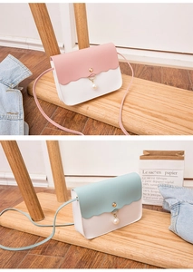 Detail of crossbody bag featuring wave edge flap, pearl pendant and metal buckle decoration