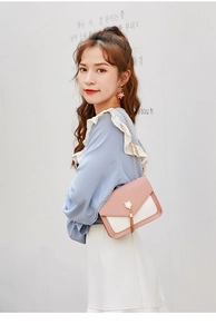 Detail of pink and white crossbody bag with cat ear metal piece and golden chain strap