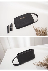 Detail of black lychee grain leather wristlet bag with gold metal Sunnycity logo