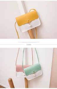 Detail of mini PU leather flap bag with wavy edges and decorative pearl pendant charms