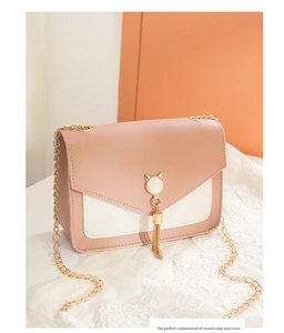 Detail of pink and beige leather crossbody bag with cat head pendant and golden tassel
