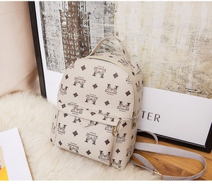 Détail d'un mini sac à dos beige avec imprimé monogramme sur un tapis blanc doux