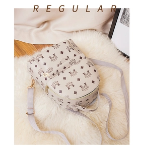 Détail d'un sac à dos beige à monogramme avec lettrage de marque sur tapis en fourrure