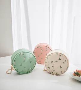 Close-up of small round purses with floral embroidery, chain strap and zipper detail