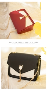 Detail of crossbody bag featuring cat-shaped metal charms and decorative tassels