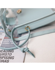 Detail of light blue transparent PVC crossbody bag with leather trim and gold magnetic clasp