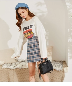 Modella che indossa una mini borsa a secchiello nera con gonna a quadri scozzesi