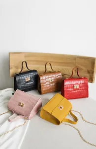 Détail de sacs bandoulière en motif crocodile en cinq couleurs avec fermoirs dorés