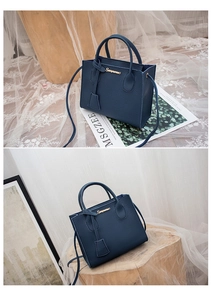 Dettaglio borsa blu navy in pelle a grana con logo dorato e tracolla rimovibile