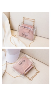 Detail of transparent bucket bag featuring gold cat-ear handles and pink inner pouch