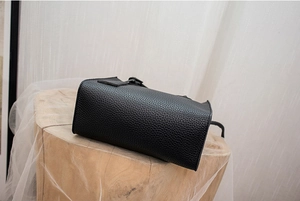 Dettaglio della trama in pelle nera e cuciture della base di questa mini borsa a secchiello