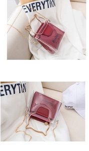 Detail of transparent PVC bucket bag featuring golden cat-ear handles and red inner pouch