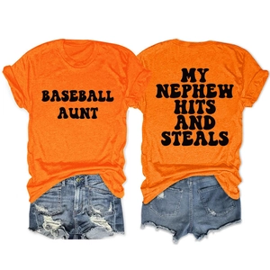 Flat lay of orange crewneck t-shirts with black baseball slogans and denim shorts