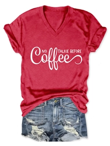 Flat lay of red V-neck T-shirt with white coffee slogan and distressed denim shorts