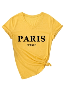 Detalle de camiseta amarilla con cuello en V, estampado de París y nudo en el bajo