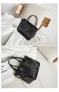 Details einer glänzenden schwarzen Lackhandtasche mit Goldkette und elegantem Griff