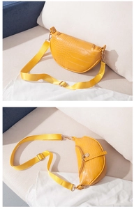 Detail of yellow crocodile pattern waist bag with wide woven strap and golden zipper