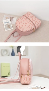 Detail view of pink mini backpack with crown pattern and gold-tone zipper pulls