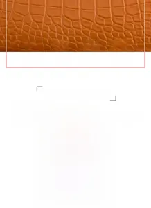 Detail of crocodile pattern texture on brown long zip wallet with wrist strap