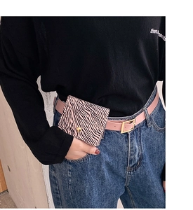 Detail of pink faux leather belt with a zebra print mini pouch on a model wearing jeans