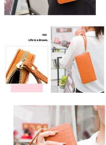 Detail of orange crocodile embossed leather clutch with gold zipper and hand strap