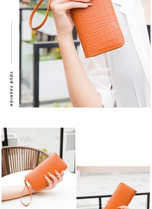 Detail of orange crocodile pattern wallet with gold zipper and stylish wrist strap