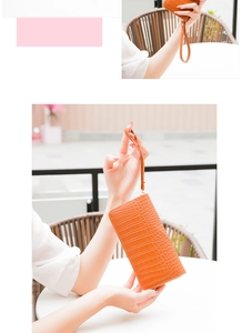 Detail view of ginger brown crocodile pattern clutch with wristlet and zipper closure