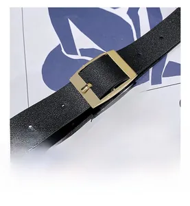 Detail of adjustable gold buckle and black lychee textured leather belt strap close-up