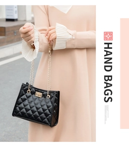 Detail of black quilted bucket bag featuring a gold chain strap and metal turn-lock closure