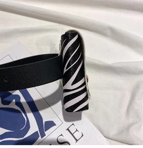 Detail view of mini zebra print waist bag with black leather belt and metal hardware