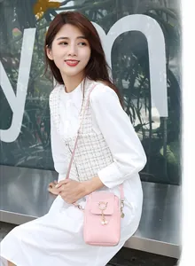Pink woven phone bag featuring a gold cat metal ring and delicate pearl tassel detail
