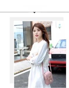 Pink woven mini square bag with pearl tassel charm shown on model in outdoor setting