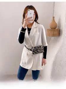 Detail of leopard print waist bag styled over a white double-breasted blazer and denim