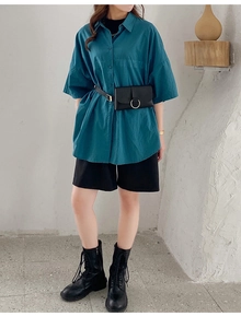 Street style look with a blue short sleeve shirt, black shorts, and a leather waist bag