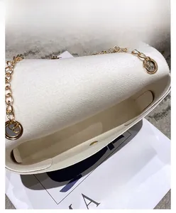 Interior detail of white textured shoulder bag showing main compartment and magnetic buckle