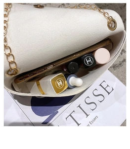 Close-up of white chain crossbody bag showing spacious interior with phone and lipsticks
