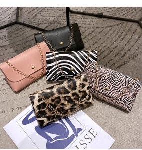 Flat lay of mini chain bags with zebra and leopard prints on a grey carpet background