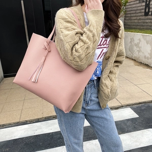 Pink pebbled leather tote bag with tassel pendant shown on street model for daily commuting