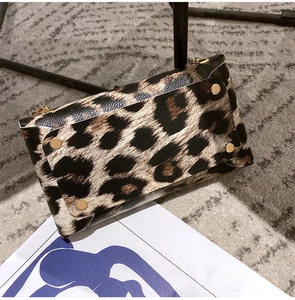 Close-up of leopard print crossbody bag featuring golden rivet details and chain link