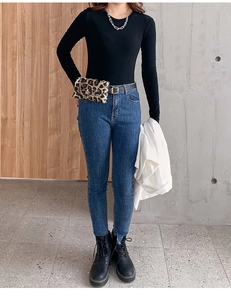 Detail of leopard print chain belt bag paired with slim high-waisted dark blue jeans