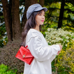 Red crocodile pattern crossbody bag with gold chain strap shown on fashion model