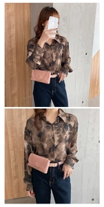 Close-up of pink leather belt bag with gold chain worn over tie-dye shirt and jeans