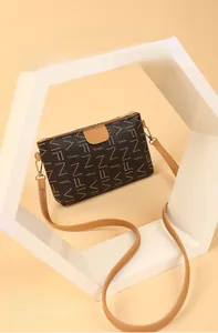 Detail of dark brown printed crossbody bag with leather strap and metal buckle