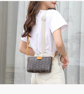 Side view of printed crossbody bag with letter pattern and orange leather puller