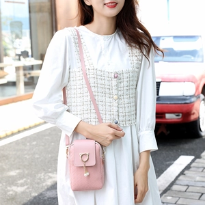 Chic pink woven phone bag with cat-ear pearl charms worn by a model in a casual street setting