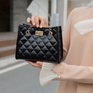Quilted bucket bag with gold chain strap and turn-lock shown in outdoor street style