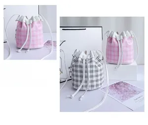 Dettaglio della borsa a secchiello con coulisse, texture a quadri rosa e neri e lacci
