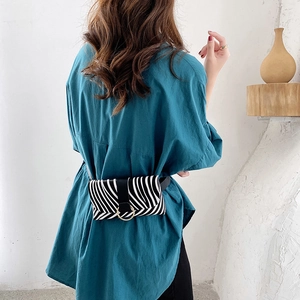 Minimalist zebra print waist bag with gold ring buckle worn over a blue shirt